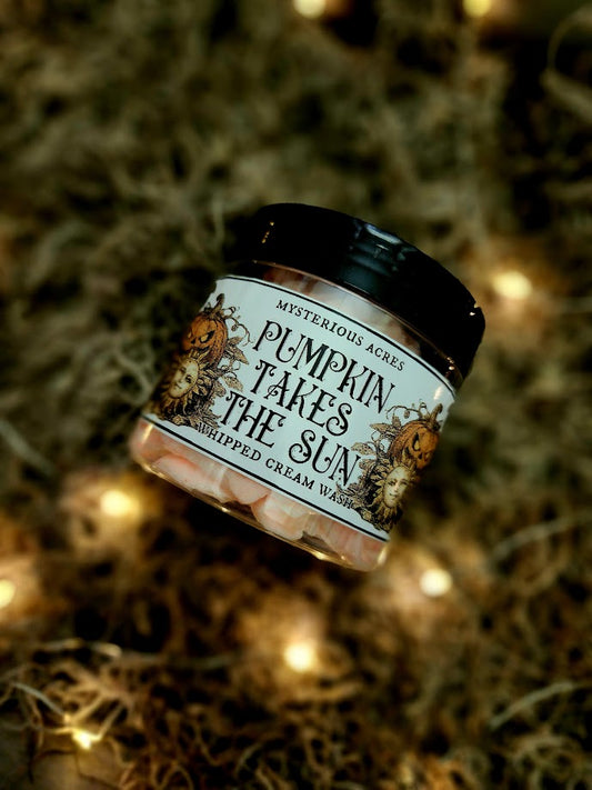 A jar of Mysterious pumpkin takes the sun whipped cream wash, featuring a black lid and a label with a gothic illustration, resting on a bed of dried moss with warm fairy lights.